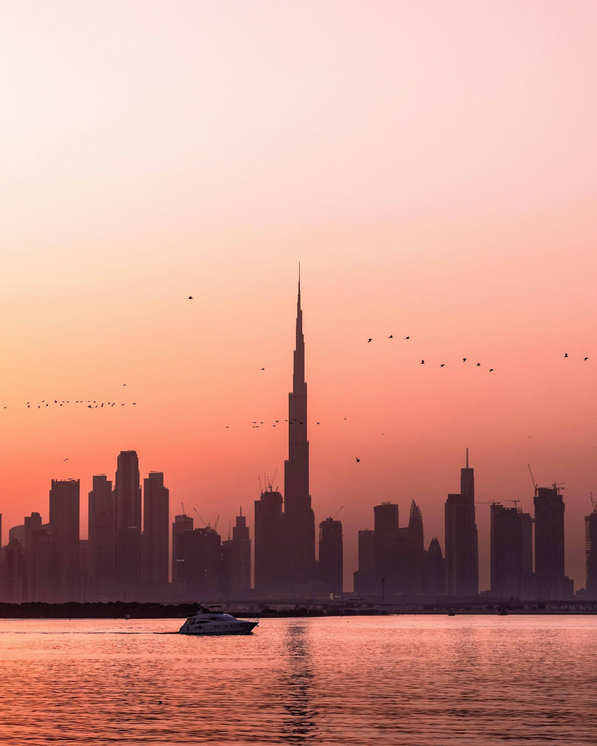 Dubai skyline and the Burj Khalifa at sunset, a yacht on the water